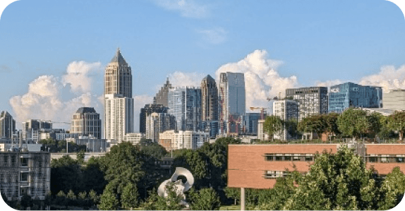 Midtown Atlanta skyline of high-rise towers above a green tree line on a clear day