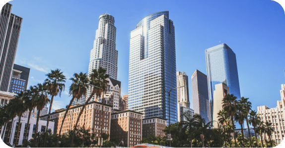 Downtown Los Angeles glass skyscrapers rising above palm trees against a blue sky
